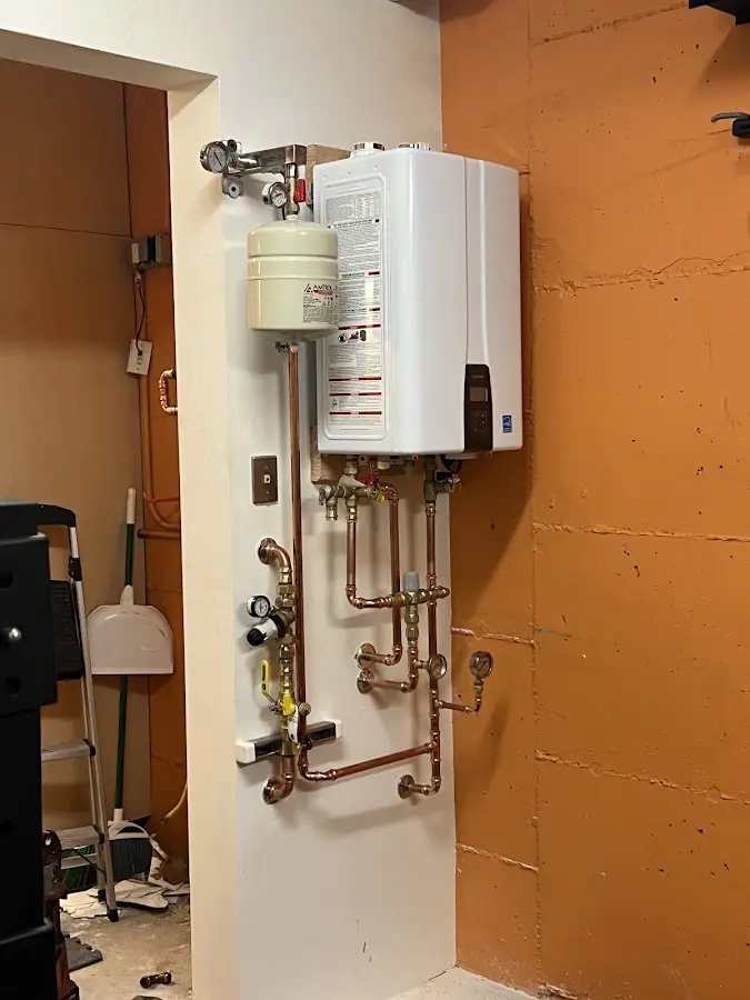 Plumbing technician inspecting water heater connections in Wauna